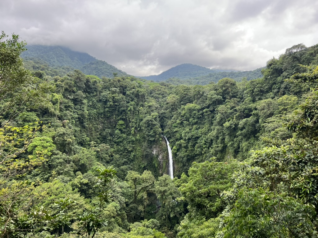 A breathtaking view of a waterfall cascading down a lush, tropical forest in Costa Rica.