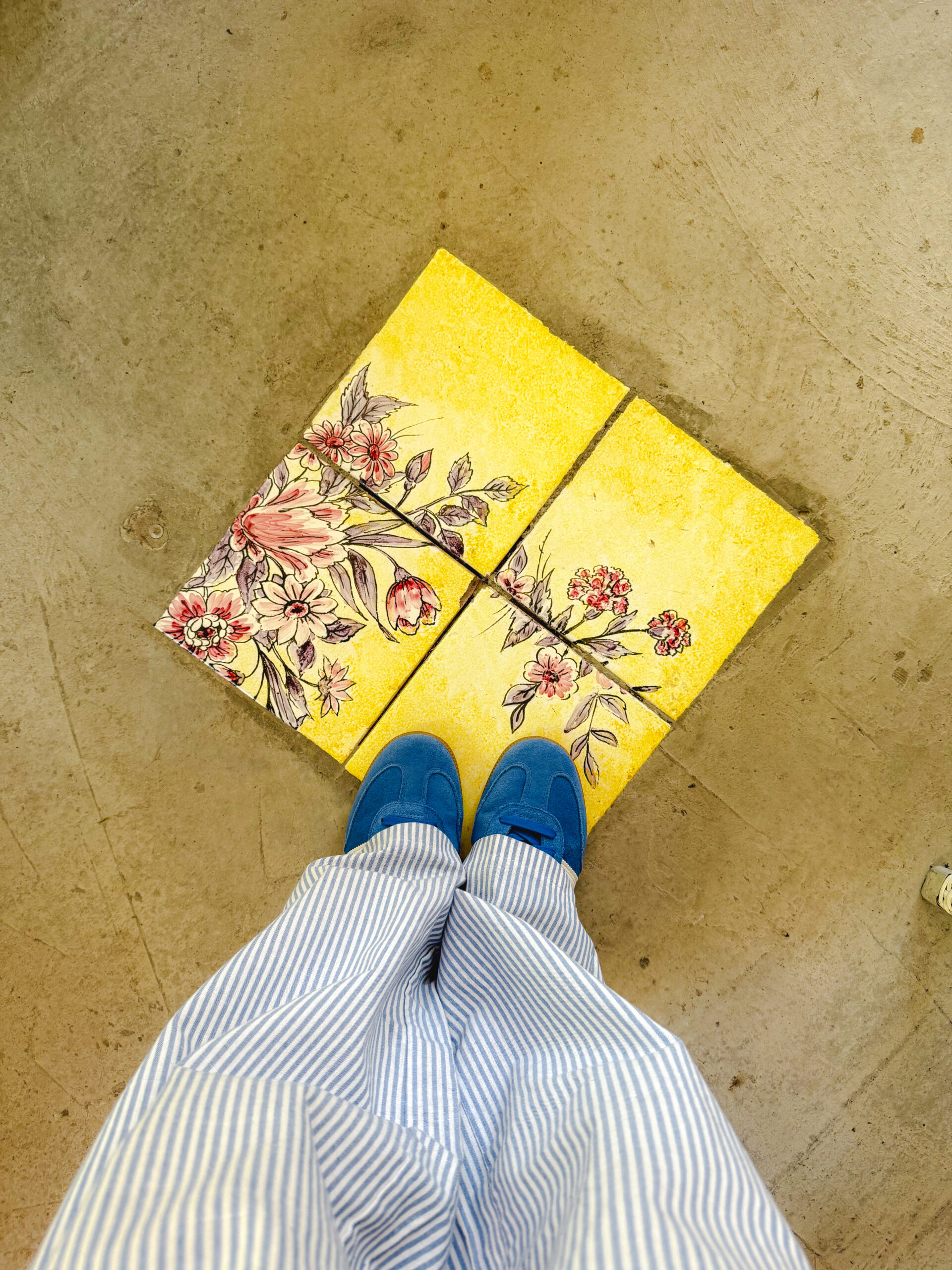 Blue striped pants and blue shoes standing on colorful Italian ceramic tiles