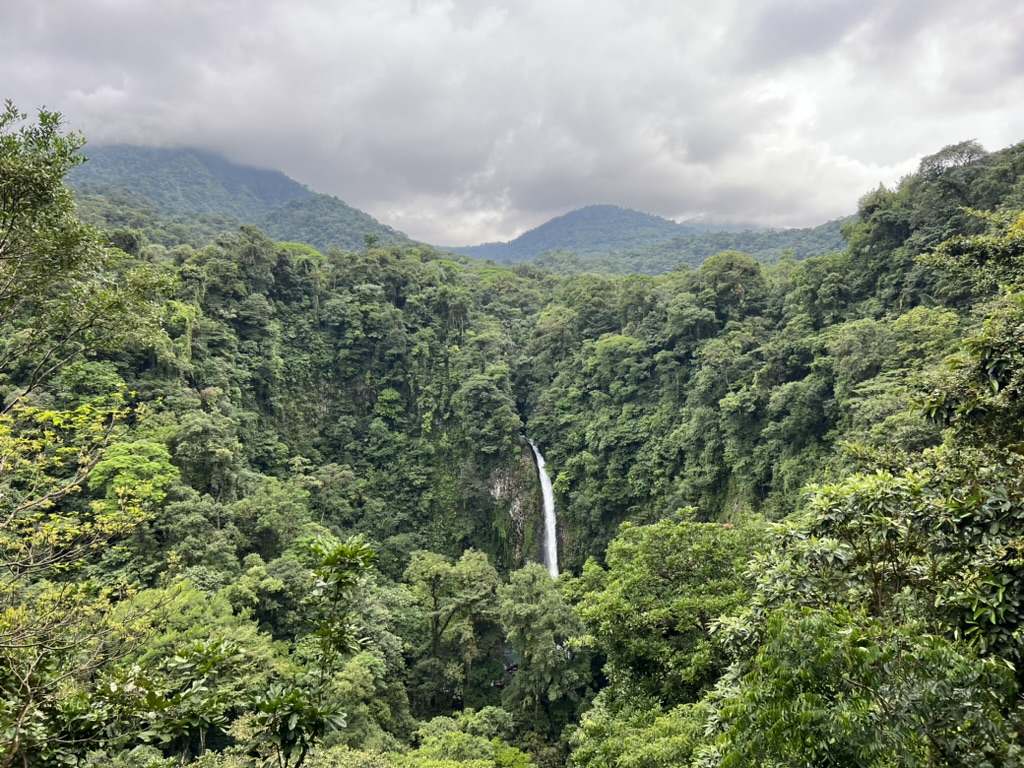 A breathtaking view of a waterfall cascading down a lush, tropical forest in Costa Rica. 